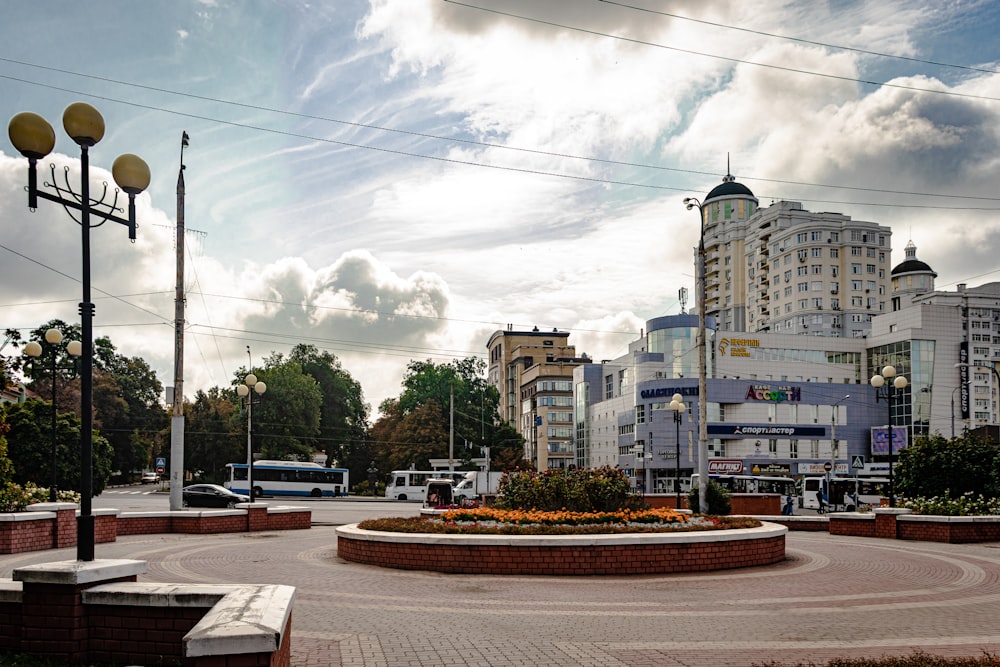 round red brick landmark with flowers, lampposts, and benches near buildings