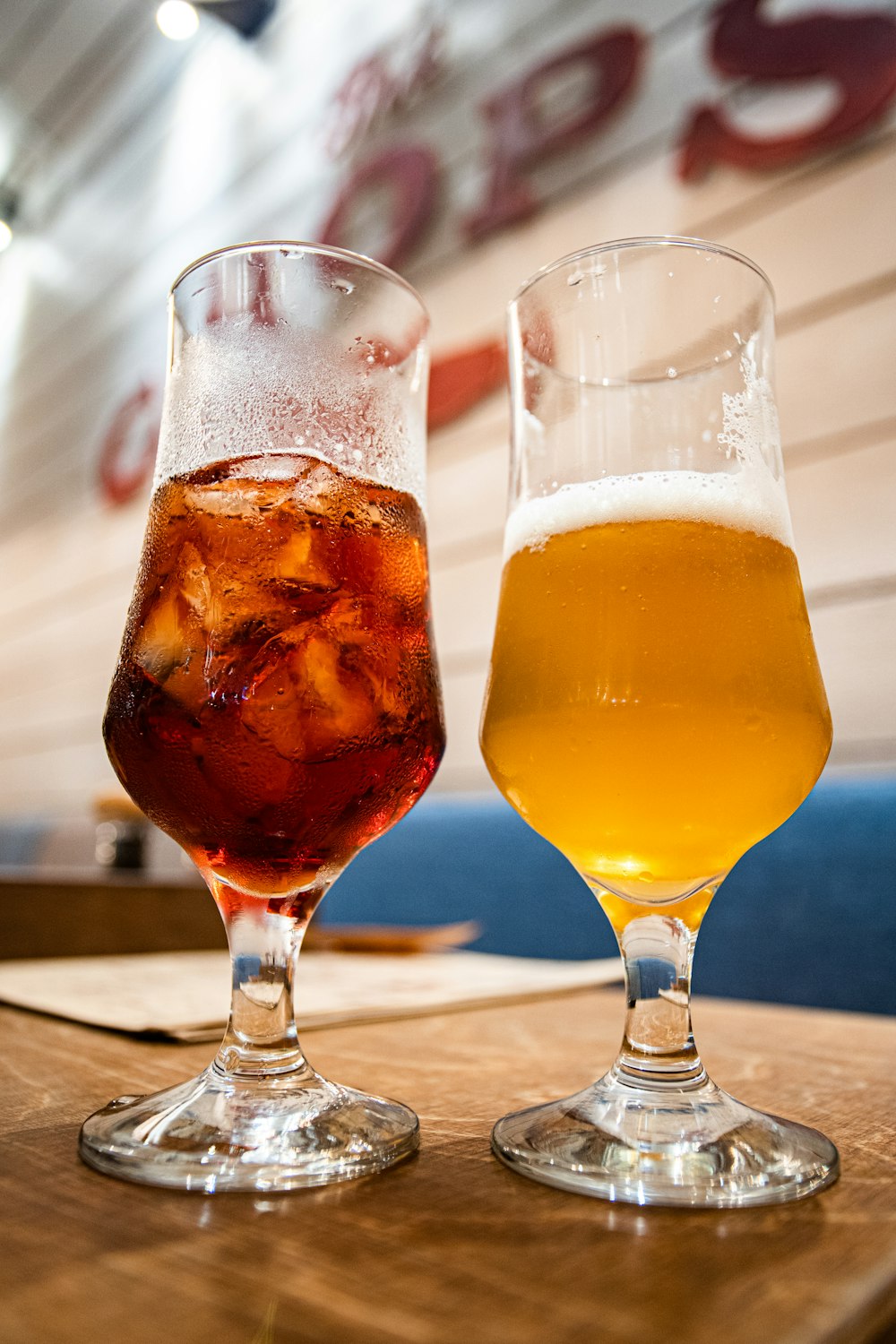 two clear footed glasses filled with beer and tea