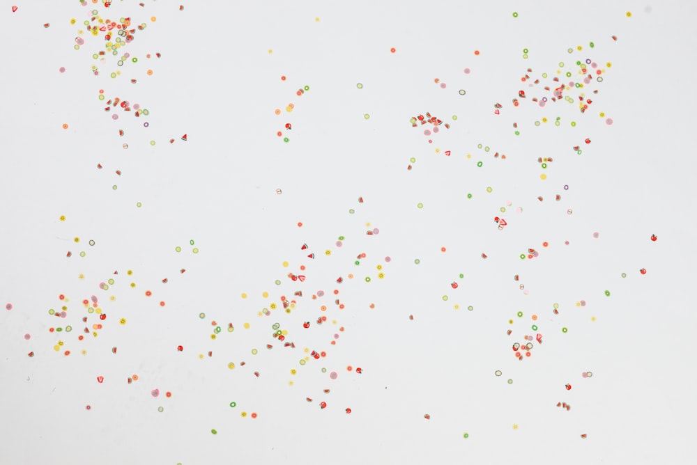 Um grupo de confetes coloridos polvilha em um fundo branco