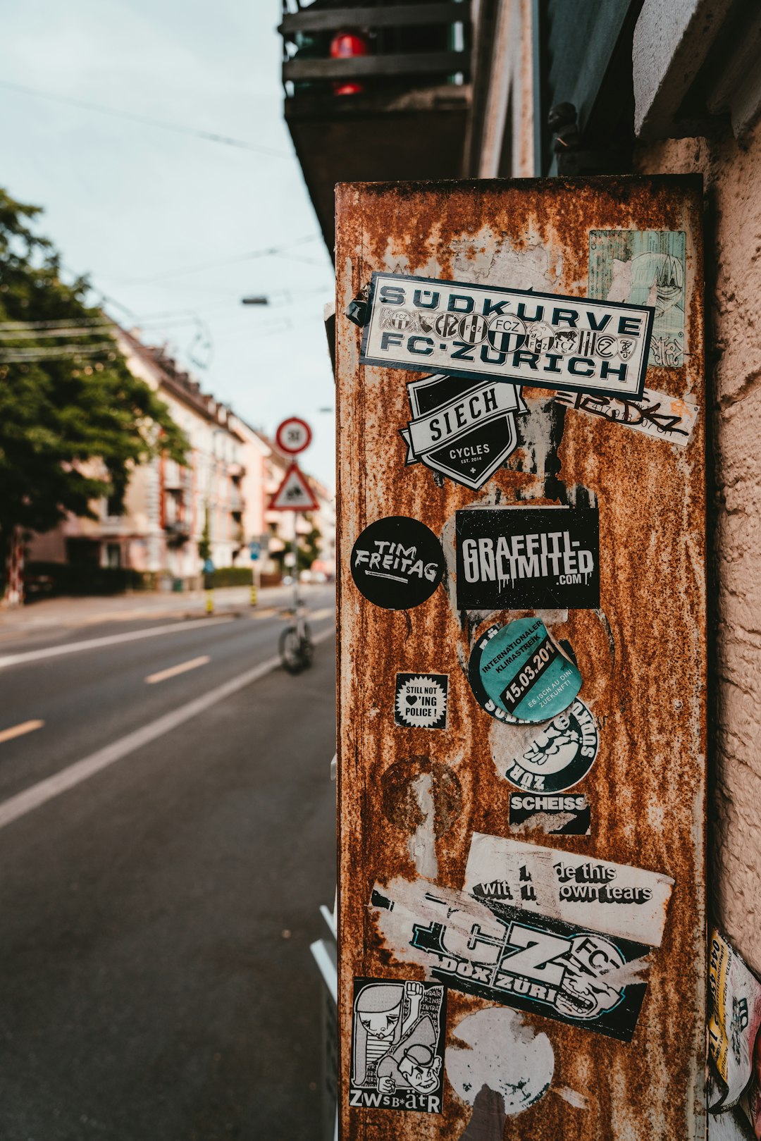 stickers on brown wall beside road during daytime