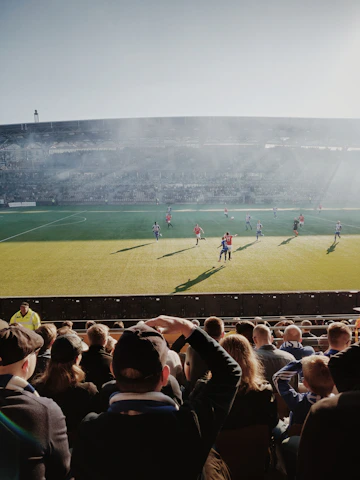A vibrant photo of a local football match with players celebrating a goal under a clear sky.