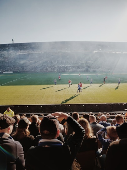 A vibrant local football tournament with players and enthusiastic supporters under clear skies.