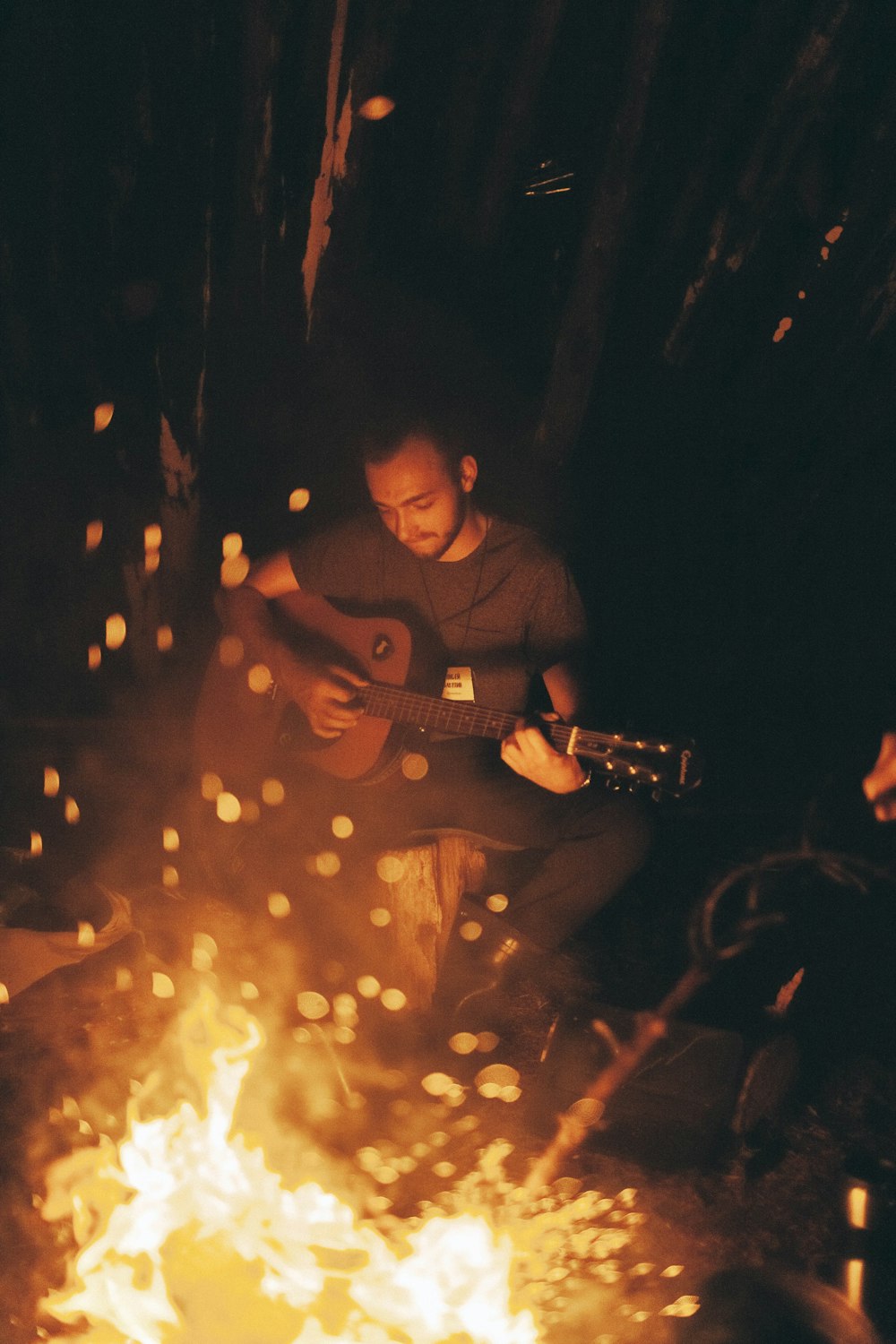 man playing guitar beside bonfire