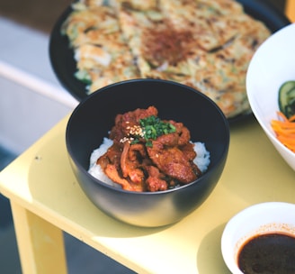 a yellow table topped with bowls of food