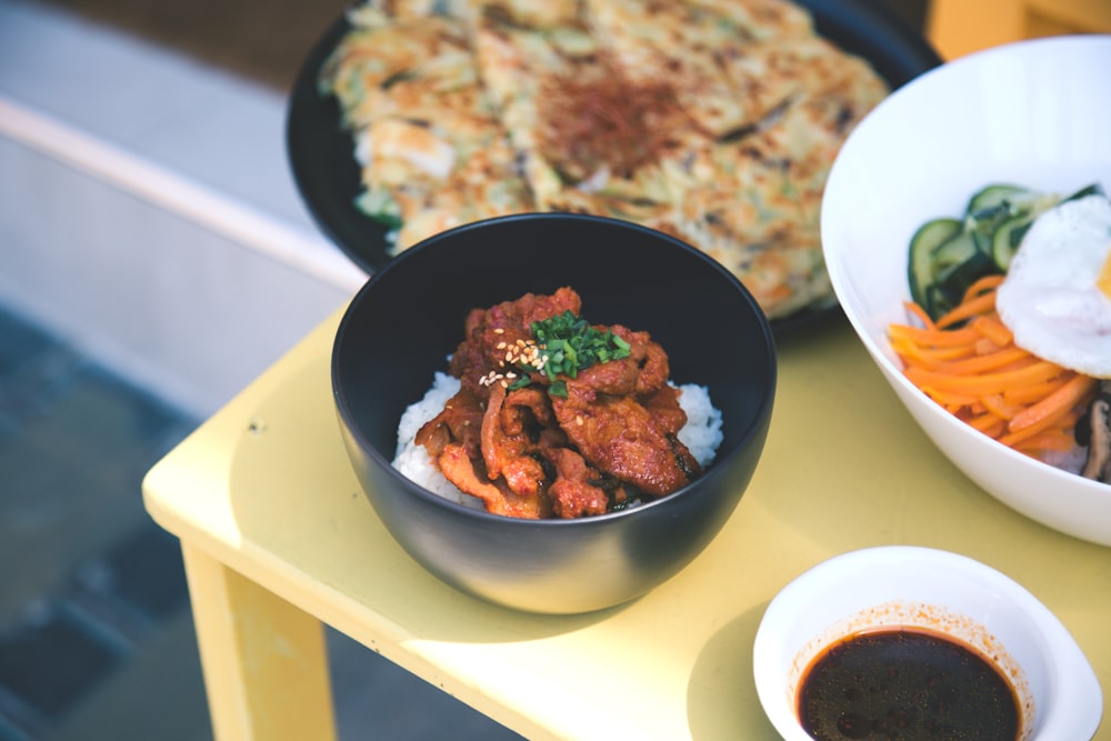 a yellow table topped with bowls of food