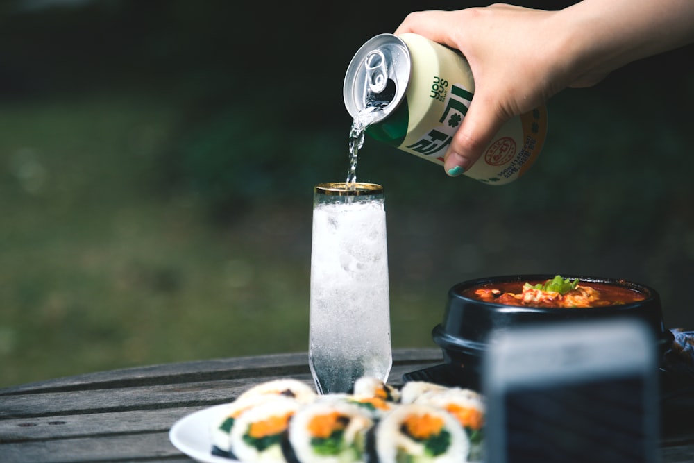 a person pouring sauce onto a plate of food