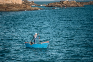 Fisherman standing confidently on a stable kayak surrounded by gentle waves.