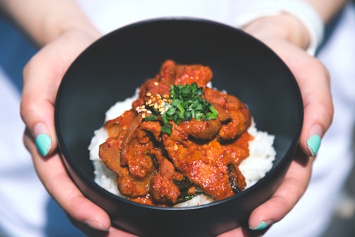 Hands sprinkling tumini seasoning over a steaming bowl of rice.