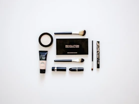 Elegant makeup brushes and vibrant lipsticks arranged on a clean white surface.