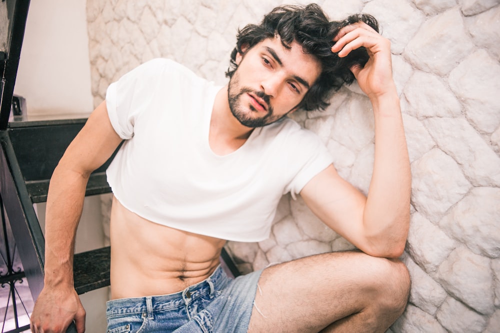 man lying on area rug wearing white crop shirt