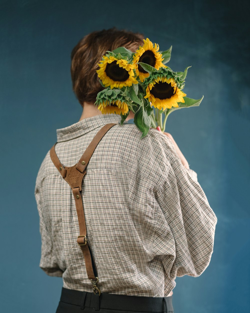 unknown person carrying three yellow sunflowers