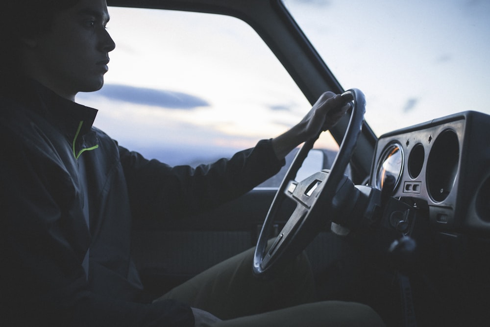 a man sitting in a car with a steering wheel