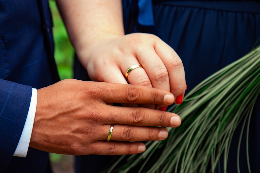 two person with gold wedding bands in hands
