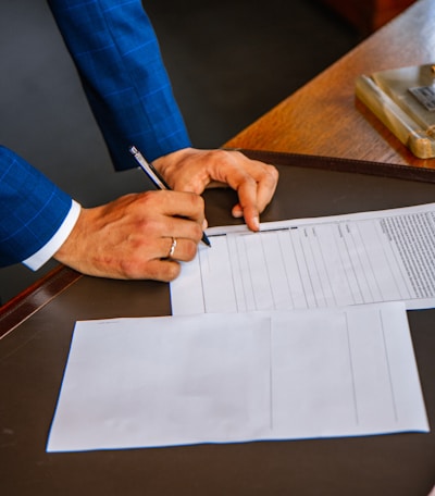 person writing on white form paper