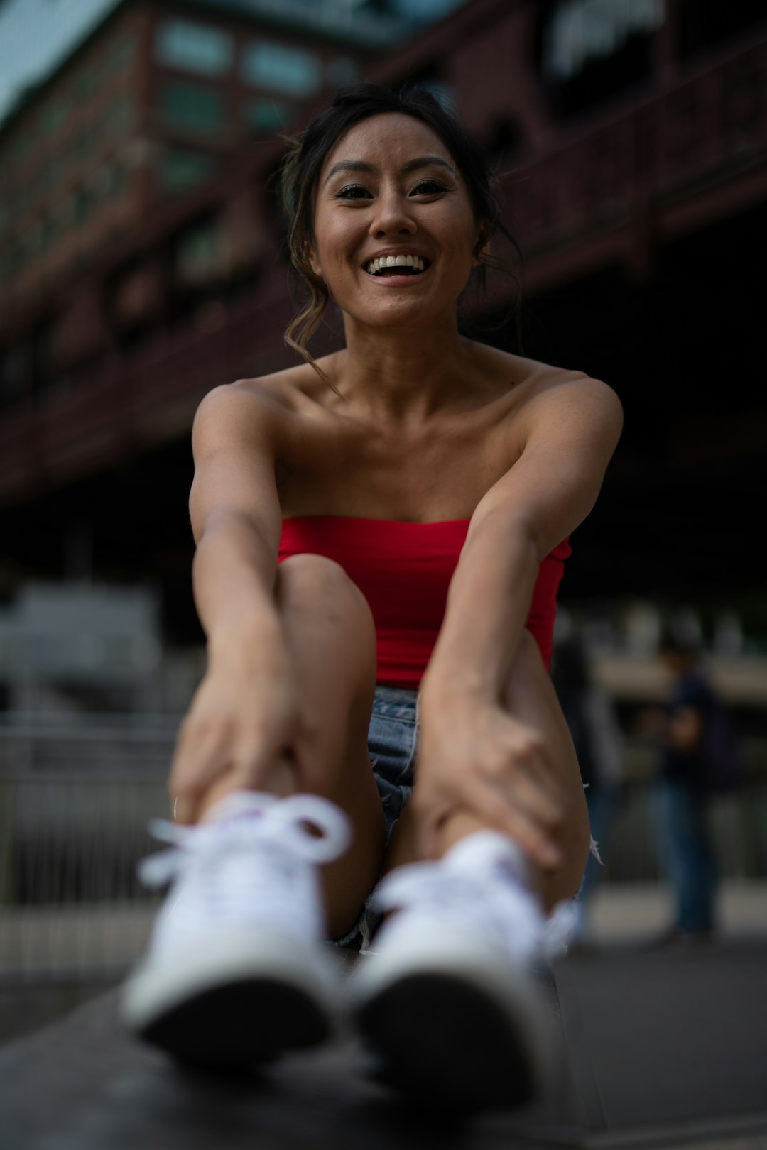 woman in red tube top and white sneakers reaching feet