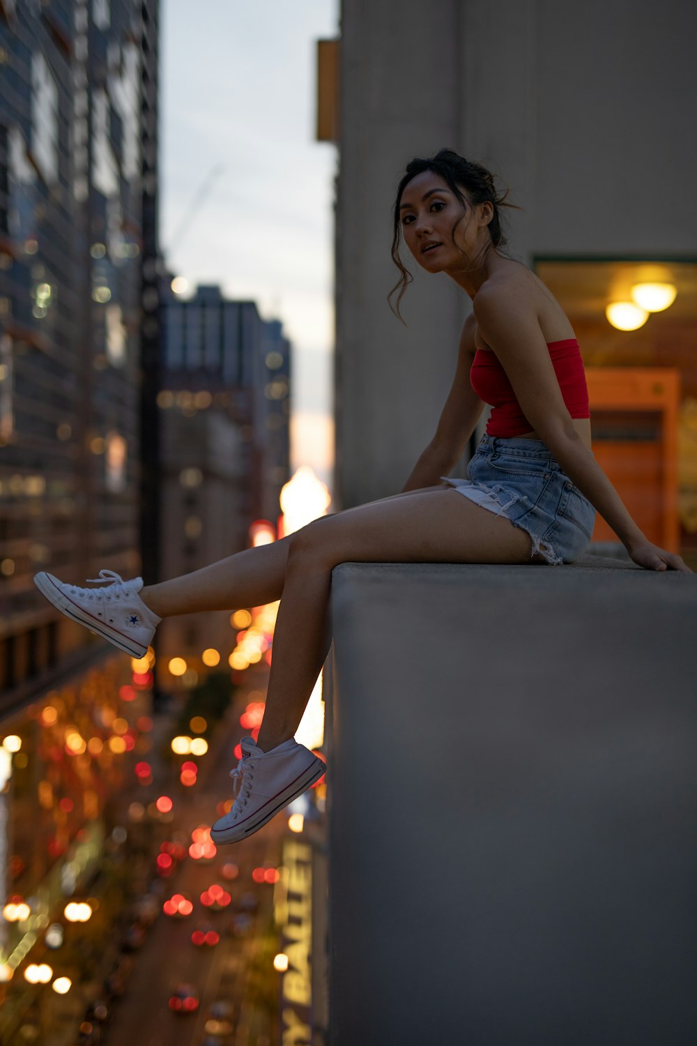 woman in red tube top and blue denim skirt sitting on rooftop