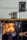 A vintage wood-burning stove with a bright fire glowing inside the open compartment. A shiny metal pot is placed on top, resting on a brass rod. The background features ceramic tiles with a decorative pattern, and the stove has ornate handles and details.