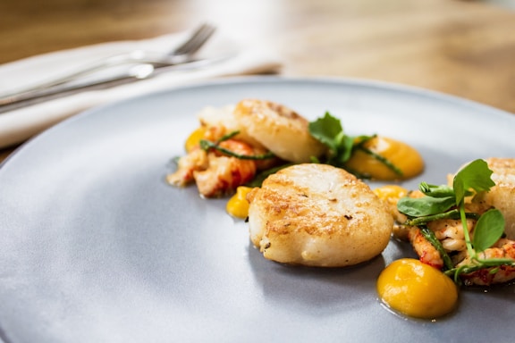 Elegant plated dish featuring seared scallops with lemon butter sauce on a white ceramic plate