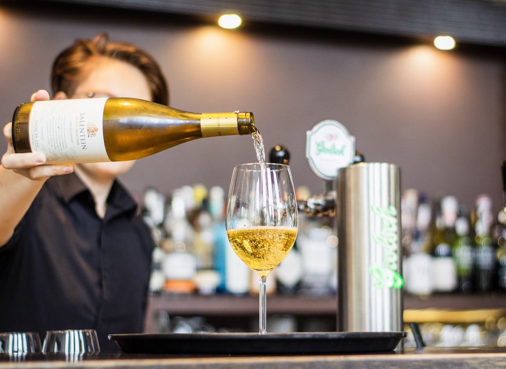 man pouring wine in wine glass