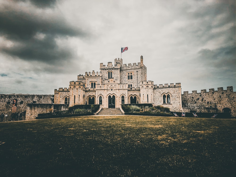 castle with flag under cloudy sky