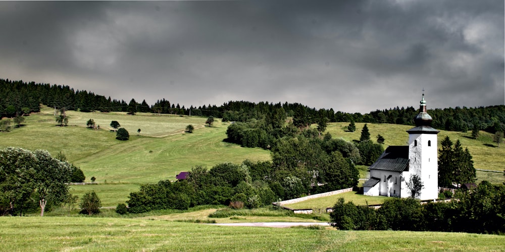 white concrete church at the bottom of hill during cloudy day