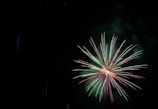 A dramatic display of neon green and gold fireworks bursting in sync.
