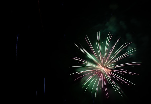 A dramatic fireworks burst shaped like a skull subtly glowing in green hues.