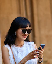 A cheerful client smiling as she checks her appointment on a smartphone.