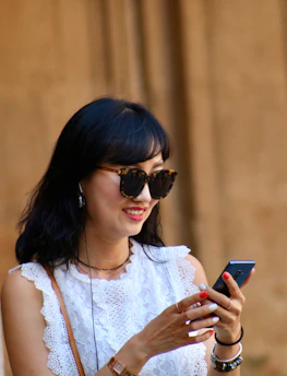 A cheerful client smiling as she checks her appointment on a smartphone.