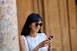 A confident professional woman smiling while checking her schedule on a sleek smartphone.