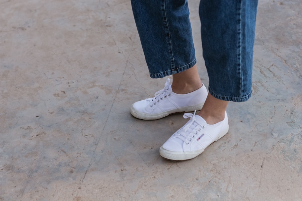 person in blue denim jeans wearing white sneakers