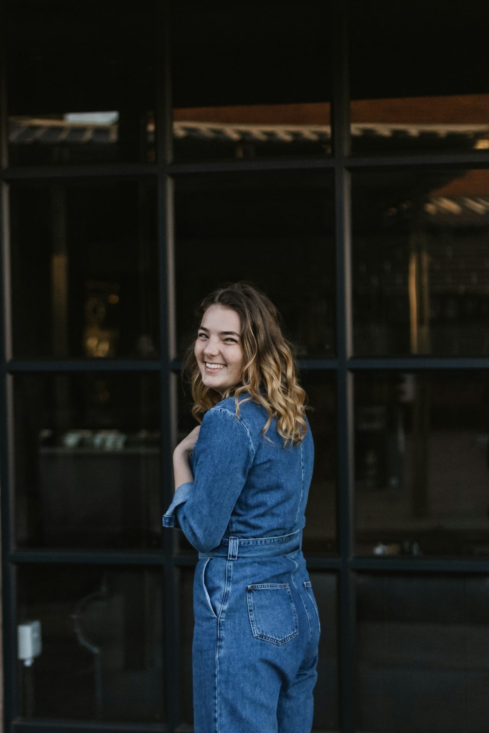 women's blue overalls while standing beside wall