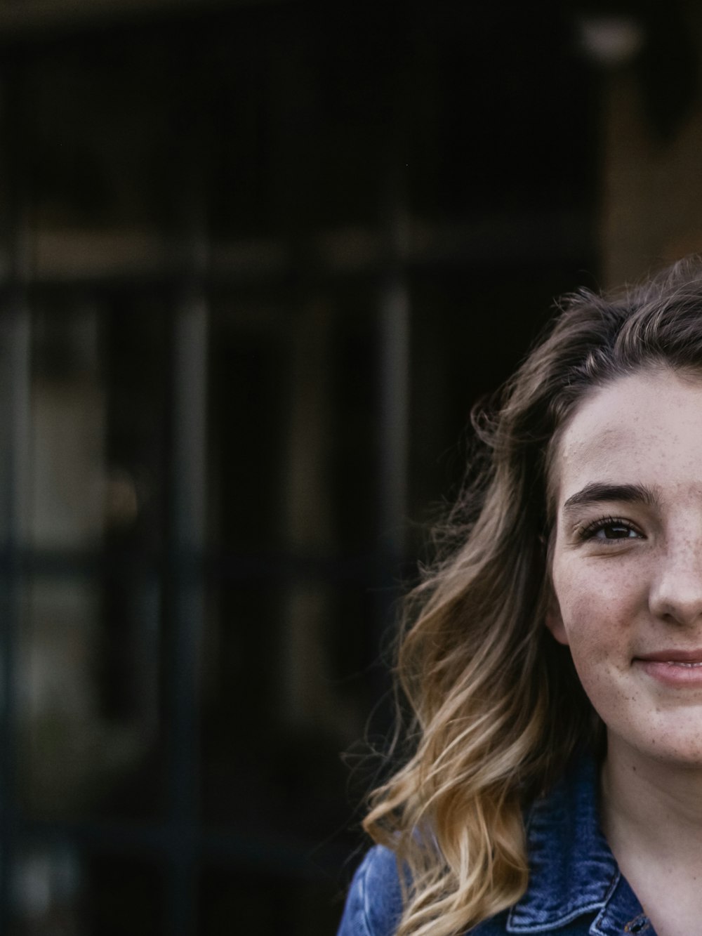 woman wearing blue jacket smiling while sowing half face