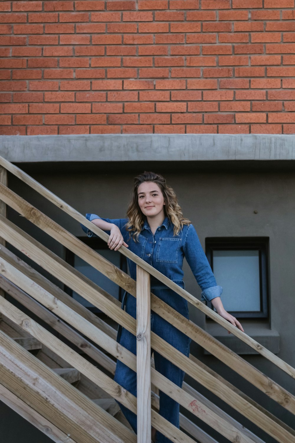 woman in blue denim shirt and jeans standing on wooden stairs