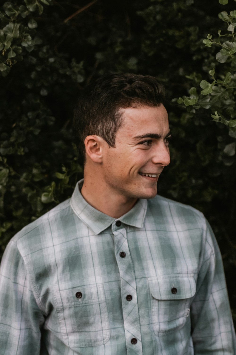 smiling man beside bushes