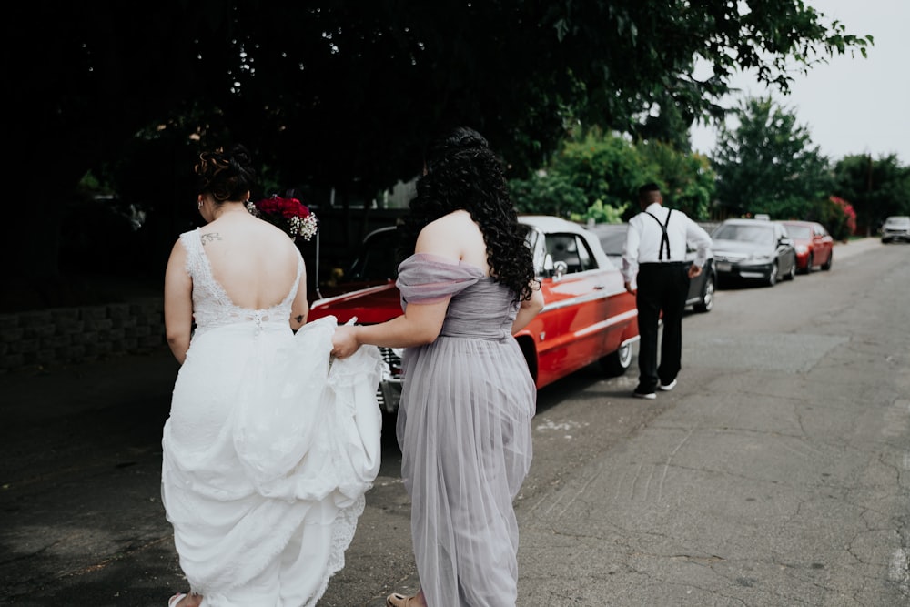 woman wearing white wedding dress walking near the red vehicle