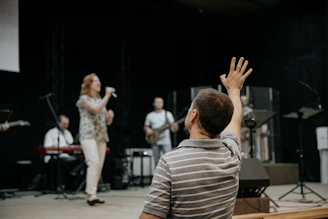 man wearing grey stripe polo shirt raising his right hand