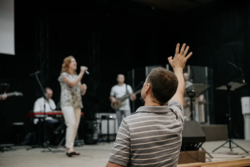 man wearing grey stripe polo shirt raising his right hand