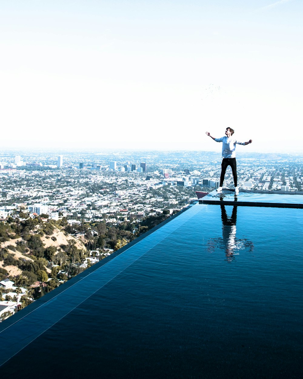 person standing on edge of swimming on rooftop