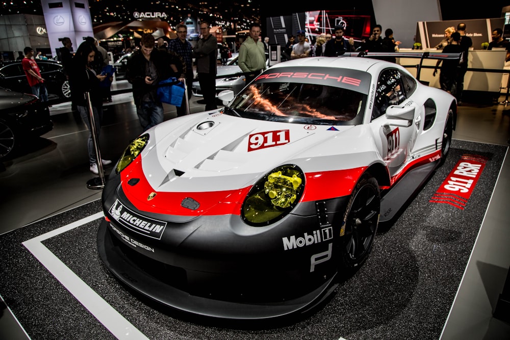 white, red, and grey Porsche 911 RSR on display at car show