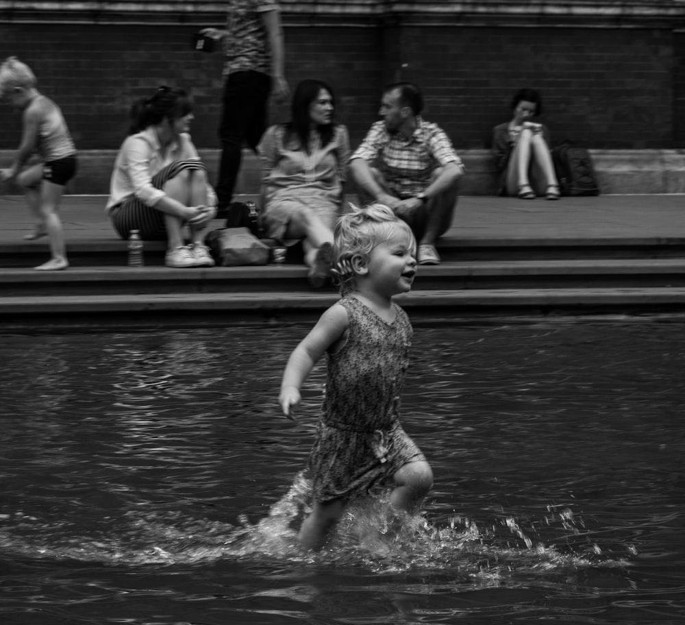 grayscale photography of child running on body of water