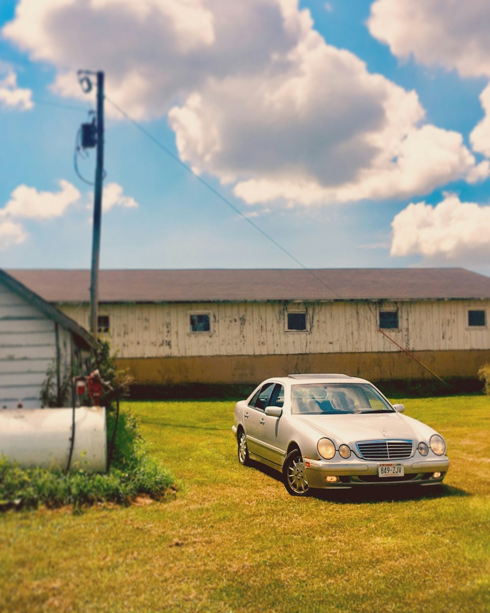 clássico cinza Mercedes Benz sedan estacionado em campo de grama ao lado de casa