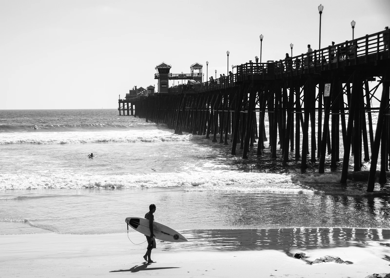Surfer standing on the shoreline while carrying a surfboard