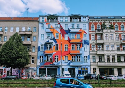 different vehicles parking near multicolored building under blue and white skies