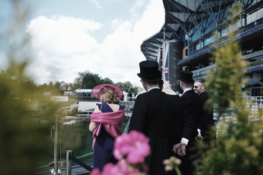 men in suit standing behind woman wearing pink hat and scarf