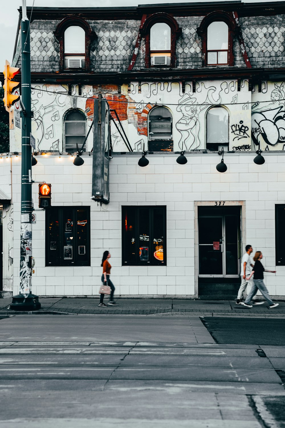 woman wearing red shirt walking besides white building