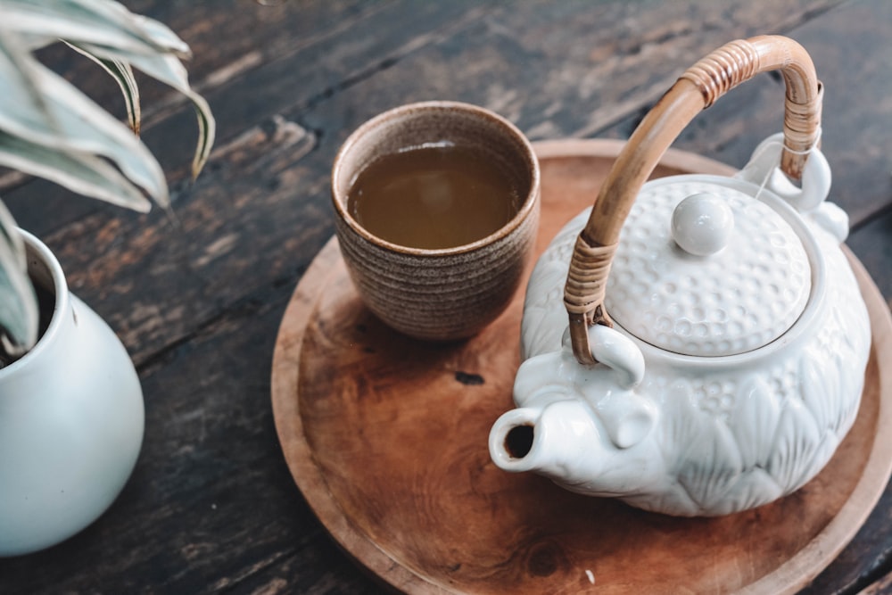 Teekanne aus weißer und brauner Keramik auf Holztablett