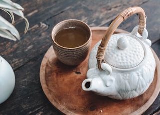 white and brown ceramic teapot on wooden tray