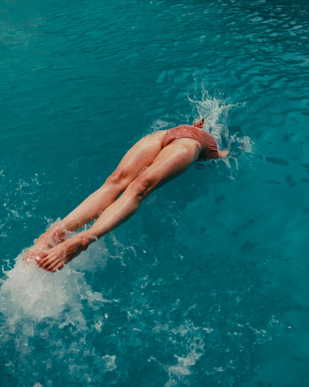 茶色の水着を着た女性が水に飛び込む