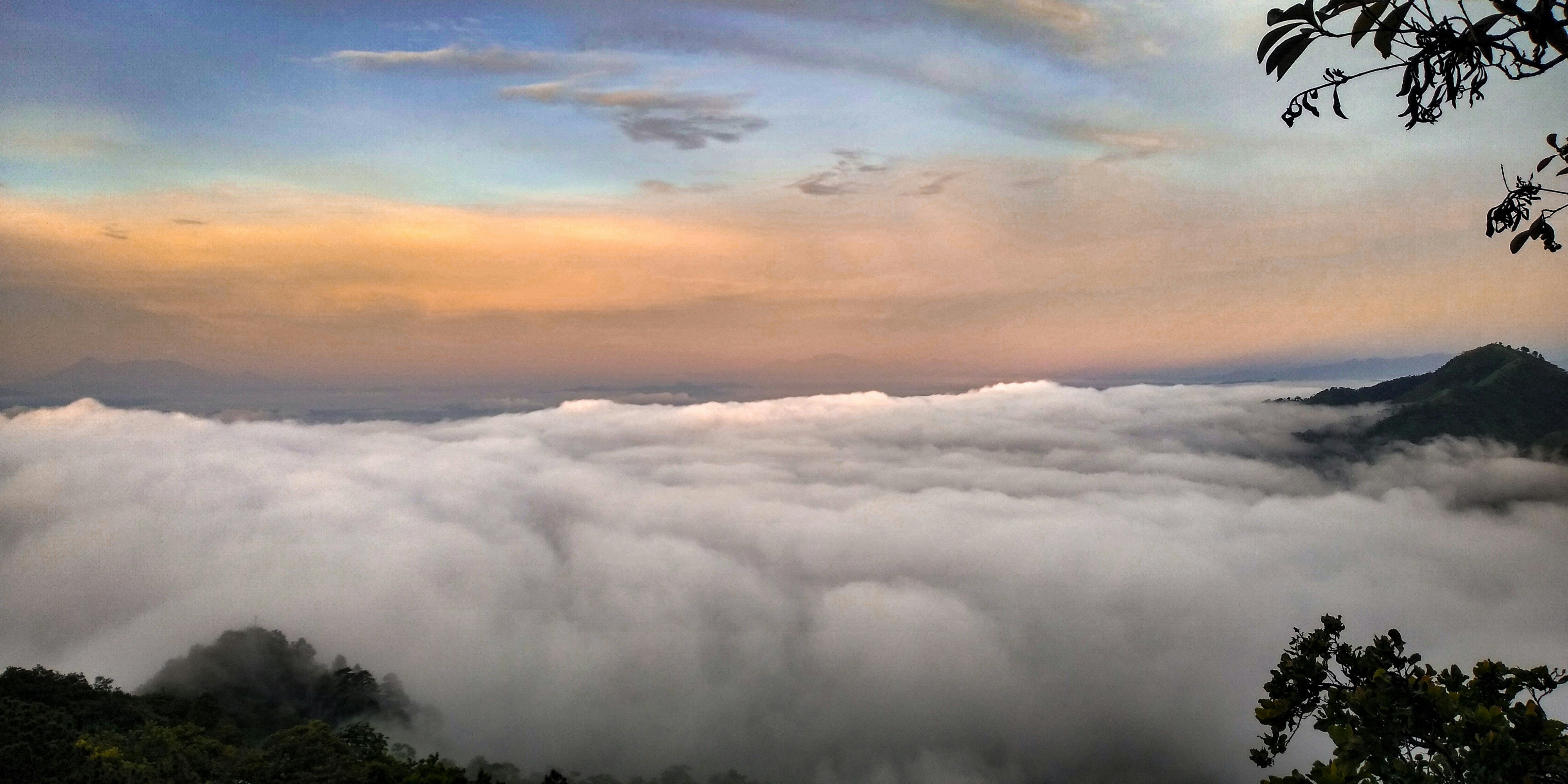 A breathtaking view of Arenal Volcano framed by lush tropical rainforest under a vibrant sunset sky.